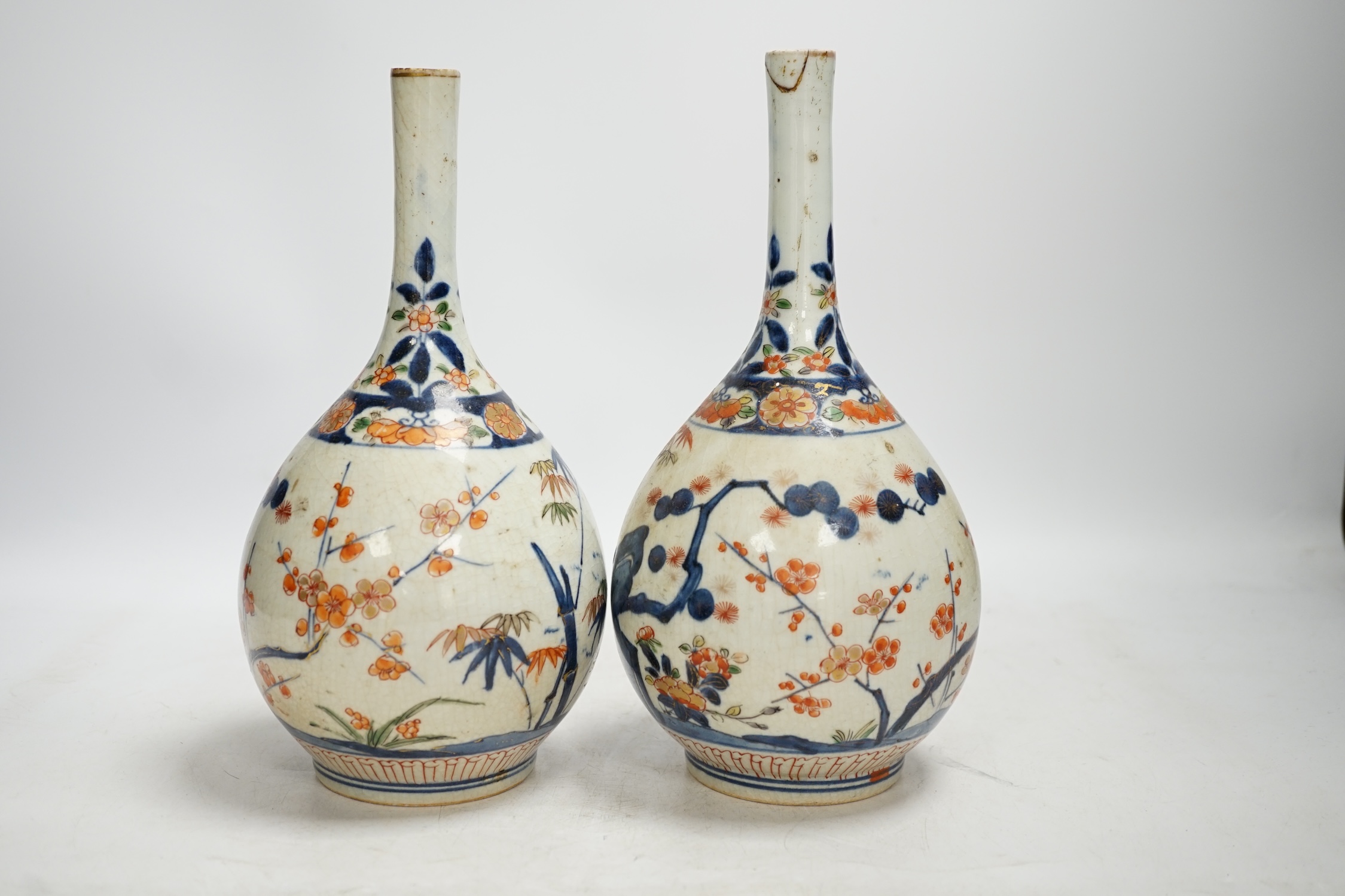 A pair of Japanese Arita bottle vases, c.1700, 24cm. Condition - heavily crazed, one with small section of neck broken and reglued